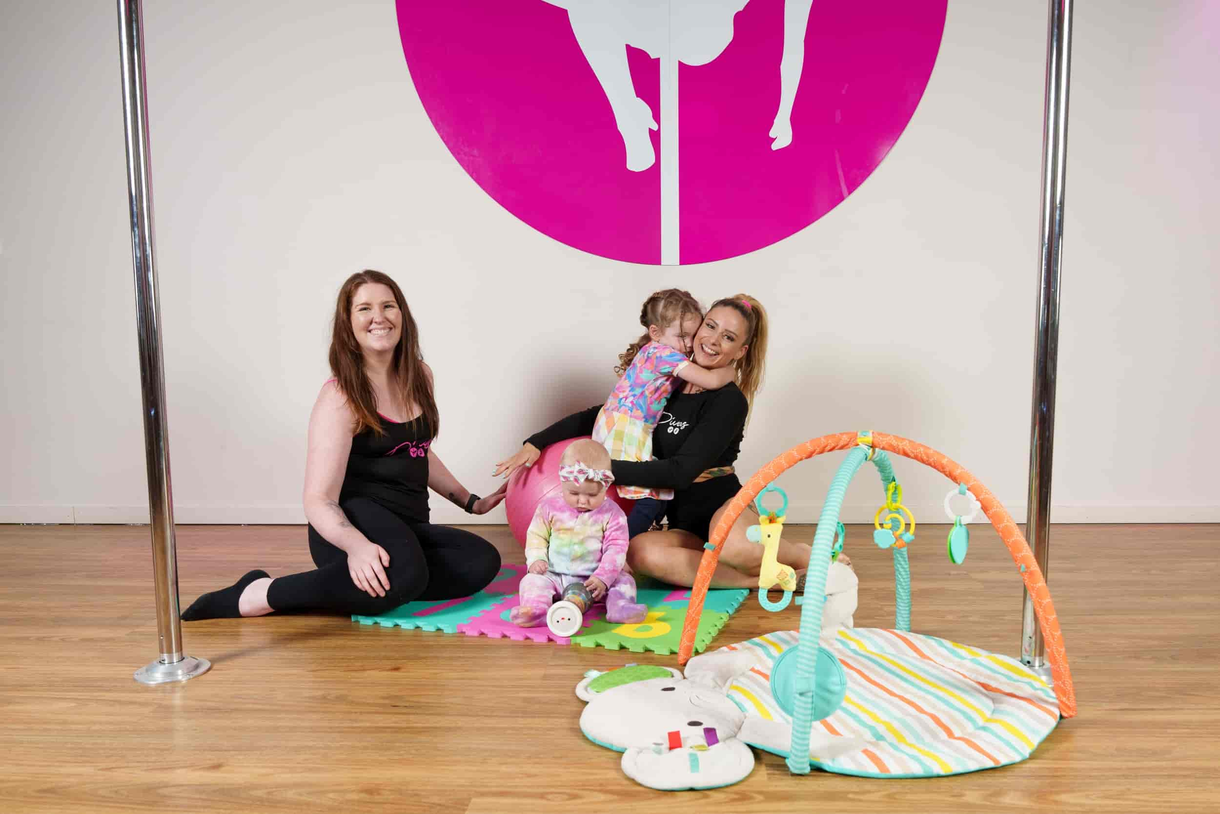 two moms taking care of their babies in a pole dancing studio